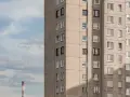Szare bloki mieszkalne, każde mieszkanie od miasta z oknami wychodzącymi na niebo. W oddali widać komin.