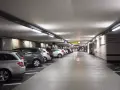 Podziemny parking z rzędami samochodów. Dostępny jest wynajem miejsca parkingowego.