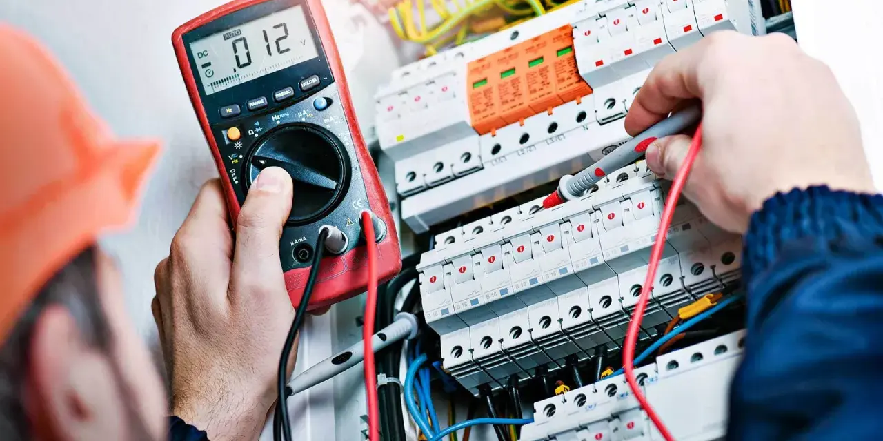 Elektryk z miernikiem w ręku, potwierdzający swoje umiejętności, niezbędne do uzyskania świadectwa kwalifikacji SEP.