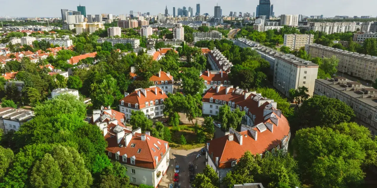 Zielony Żoliborz Oficerski z charakterystyczną architekturą i panoramą miasta w tle.