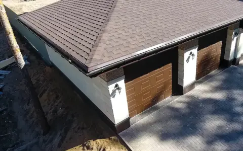 Nowy dach papa na garażu z brązowymi drzwiami i ozdobnymi słupkami.