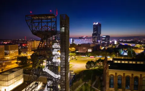 Wieżowiec kopalni węgla obok nowoczesnych budynków tworzy kontrast w nocnym megapolis.