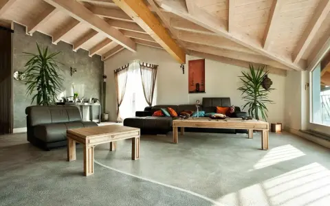 Nowoczesny salon z drewnianymi belkami i gładką, szarą posadzką z żywicy.