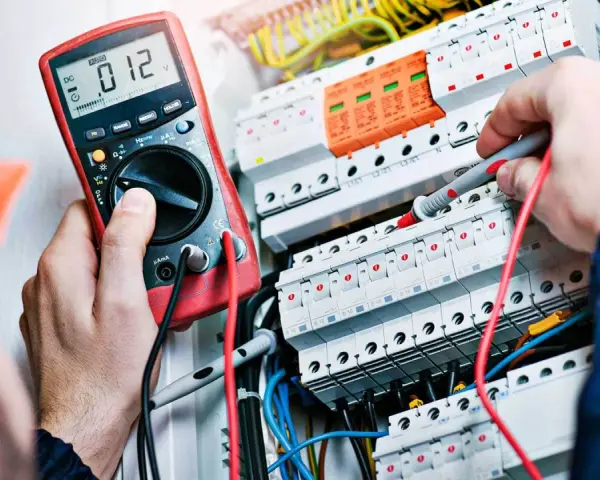 Elektryk z miernikiem w ręku, potwierdzający swoje umiejętności, niezbędne do uzyskania świadectwa kwalifikacji SEP.