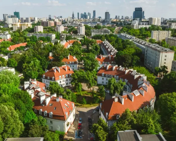 Zielony Żoliborz Oficerski z charakterystyczną architekturą i panoramą miasta w tle.