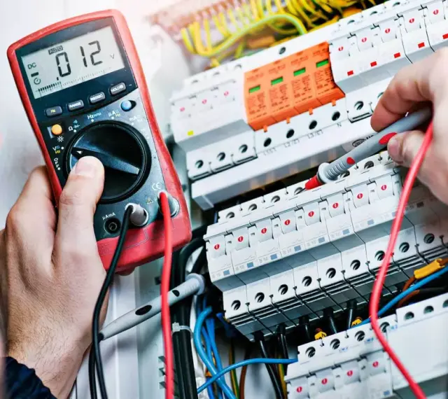 Elektryk z miernikiem w ręku, potwierdzający swoje umiejętności, niezbędne do uzyskania świadectwa kwalifikacji SEP.